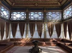 a living room filled with lots of furniture and large window covered in drapes on the ceiling