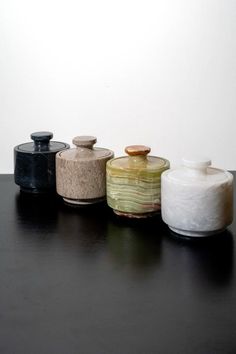 four jars sitting on top of a black table