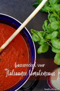 a blue bowl filled with tomato sauce next to basil leaves and a can of beer