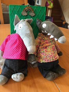 two stuffed animals sitting on top of a wooden table