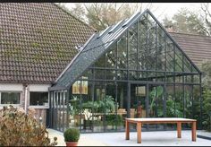 a glass house with a wooden bench in the front yard