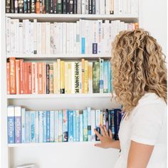 a woman standing in front of a book shelf filled with books