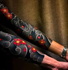 a woman's arm and leg covered in tattoos with red flowers on the side