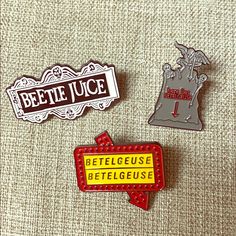 three pins that are on top of a piece of cloth with the words beetle juice