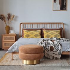 a bedroom with a bed, ottoman and pictures on the wall