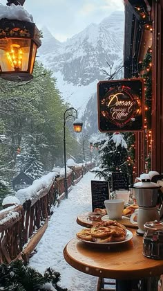 a wooden table topped with plates of food next to a snow covered mountain side restaurant