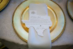 a place setting with white napkins and gold plates