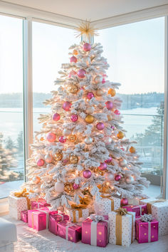 a white christmas tree with pink and gold ornaments in front of a large windowsill