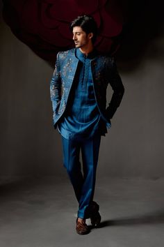 Editor's Note Featuring a new shade of teal in this short jacket with intricate linear floral hand embroidery. Highlighted with antique moti, dabka and shades of brown. Paired with a tone-on-tone short length kurta and tapered trousers. Fabric: Linen silk Color: Teal blue Components: Short jacket, kurta and trousers Occasion: Groom Fit: Regular Note: Product colour may slightly vary due to photographic lighting sources Care: Dry clean only About the Designer After establishing himself as the lea Jatin Malik, Indian Wedding Clothes For Men, Floral Hand Embroidery, Blouse Yoke, Modern Suits, Teal Shorts, Royal Look, Shades Of Teal, Tapered Trousers