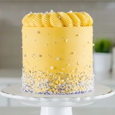 a yellow cake with white frosting and sprinkles on top sitting on a plate