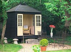 a small black shed sitting in the middle of a lush green yard with lots of trees