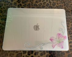 an apple laptop computer sitting on top of a leopard print tablecloth with a pink flower