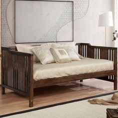 a wooden daybed with pillows on top of it in a living room next to a lamp