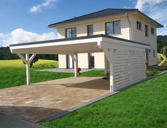 a house with a covered patio in the middle of a grassy area next to a driveway