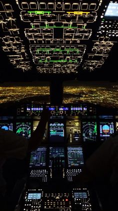 the cockpit of an airplane is lit up at night with lights in the sky and on the ground