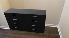 a black filing cabinet sitting on top of a hard wood floor next to a wall