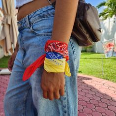 a woman wearing a colorful bracelet with red, yellow and blue ribbons on her wrist