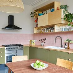 a bowl of green apples sitting on top of a wooden table next to a stove