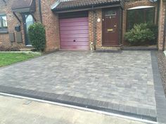 a brick driveway in front of a house with purple garage doors and brown shutters