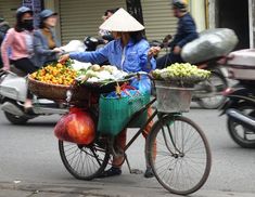 a person riding a bike with baskets full of fruit on it's back in the street