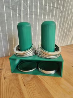 two green salt and pepper shakers sitting on top of a wooden table