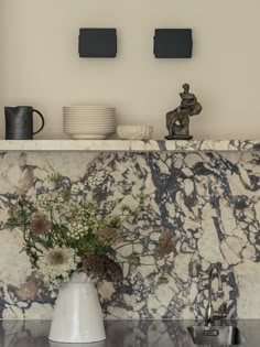 a vase with flowers sitting on top of a kitchen counter