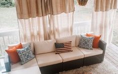 a couch sitting on top of a wooden floor next to a window covered in curtains