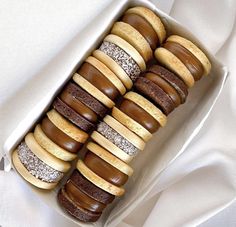 a box filled with lots of different types of donuts on top of a white cloth