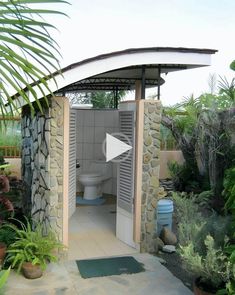 a small outdoor toilet in the middle of a garden with plants and trees around it