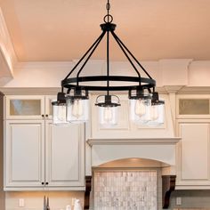 a kitchen with white cabinets and a black chandelier hanging from the ceiling over an island