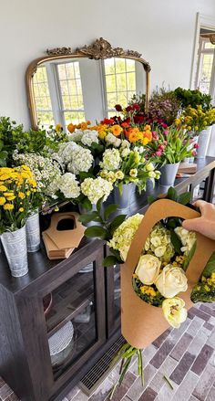 a bunch of flowers that are sitting on a table in front of a mirror and vases