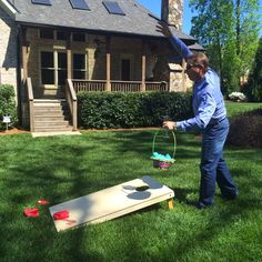 a man throwing a frisbee at a game on the grass in front of a house