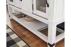 a white cabinet with glass doors and plates on the bottom shelf next to a rug