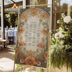 a sign that has flowers on it in front of a building with windows and tables