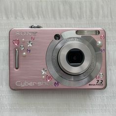 a pink camera sitting on top of a white blanket