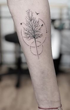 a person's leg with a tree tattoo on the left side of their arm