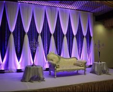 the stage is set up for an event with purple lights and drapes on it