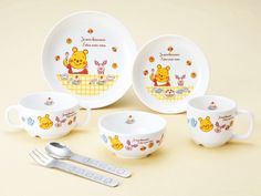 winnie the pooh baby feeding set with spoons and fork on yellow tablecloth