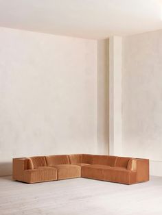 a corner sofa in an empty room next to a wall with no one on it