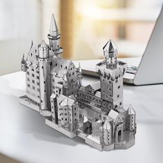 a laptop computer sitting on top of a white table next to a castle shaped model