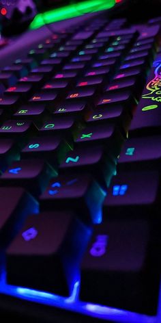 a close up view of a keyboard with neon lights on the keys and backlits