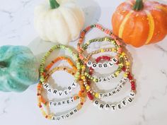 four bracelets with words on them sitting next to two pumpkins and an apple