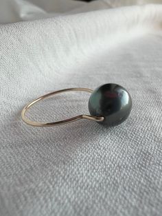 Discover the understated elegance of this size 5 Dark Grey Tahitian Pearl Ring.* Featuring a premium 8-9mm Tahitian pearl at its center. The unique setting features the pearl perched atop gold-filled wire, creating an illusion of floating elegance. This minimalistic design highlights the pearl's iridescence, making the ring versatile for both casual and formal occasions. Crafted for durability and comfort, the gold-filled wire ensures a lasting, tarnish-resistant finish. Ideal for a minimalist statement or a stylish stacked ensemble, this ring is a timeless addition to any collection, offering a touch of class and refined beauty. Handcrafted in our Texas studio with the highest quality materials.  *The item shown in the picture is available for immediate shipment. *For questions about diff Yellow Gold Tahitian Pearl Ring, Tahitian Pearl Ring, Gold Filled Ring, Tahitian Pearls, Minimalistic Design, The Pearl, Understated Elegance, Tahiti, Stackable Rings