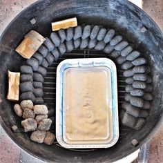 an outdoor grill with rocks and food cooking in it