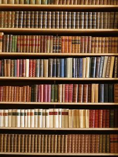 a book shelf filled with lots of different colored books on top of eachother