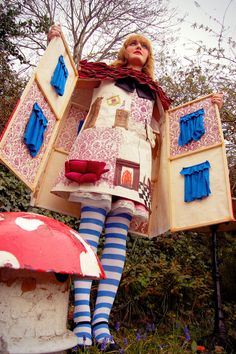 a woman is dressed up as a mushroom and holding two pieces of furniture in her hands