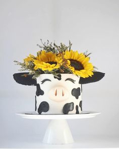 a cake decorated with sunflowers and a cow face on top is sitting on a plate