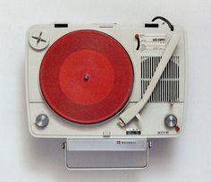 an old fashioned turntable with a red disc on the top and silver trims