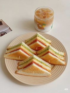 four sandwiches on a plate next to a drink