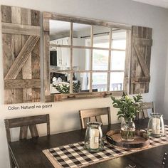 a dining room table with a vase on it and a mirror hanging over the table